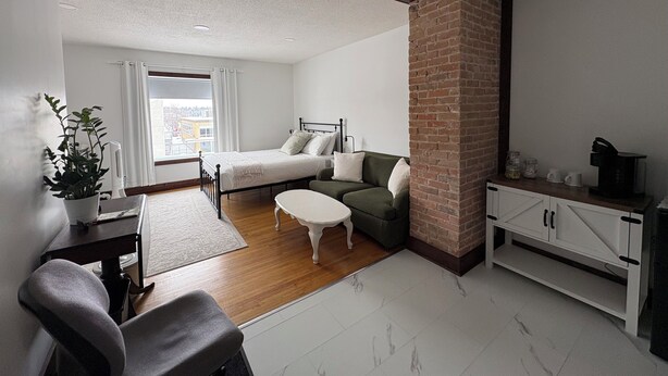 Una habitación moderna con cama, sofá, mesa de comedor y zona de cocina.