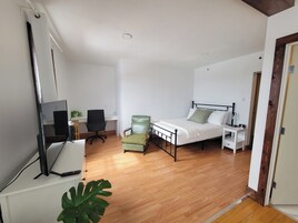 Un dormitorio con cama, mesita de noche, silla, escritorio y televisión.