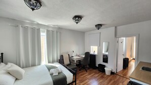 Un dormitorio con cama, escritorio, silla, espejo y baño.