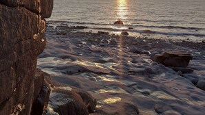 A rocky shoreline with the sun setting over the ocean. - Fundy Fantasy Oceanfront Cabin. Offgrid romantic getaway. (Granville Ferry)