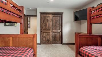 A room with bunk beds, a wooden door, a flat-screen TV, and a carpeted floor.