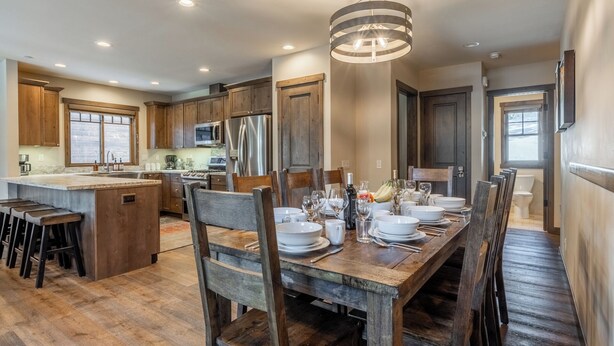 Una cocina amplia con armarios de madera, una isla central y un comedor dispuesto para seis personas.