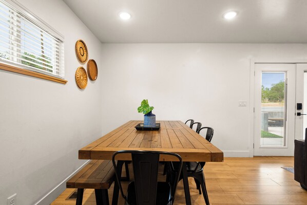 A dining area with a wooden table, black chairs, and a potted plant. - Modern Mesa (Moab)