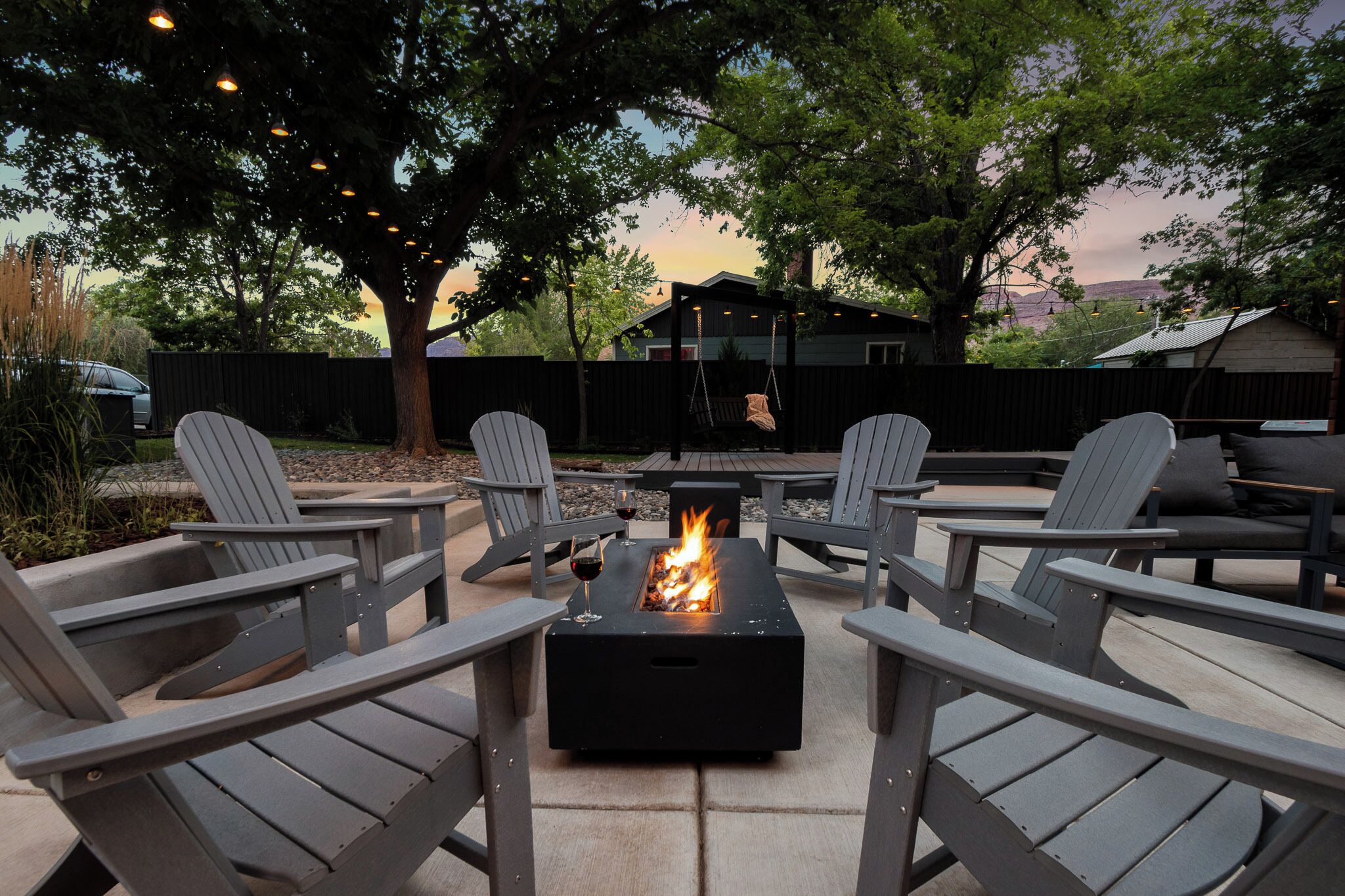 An outdoor seating area with Adirondack chairs and a fire pit.