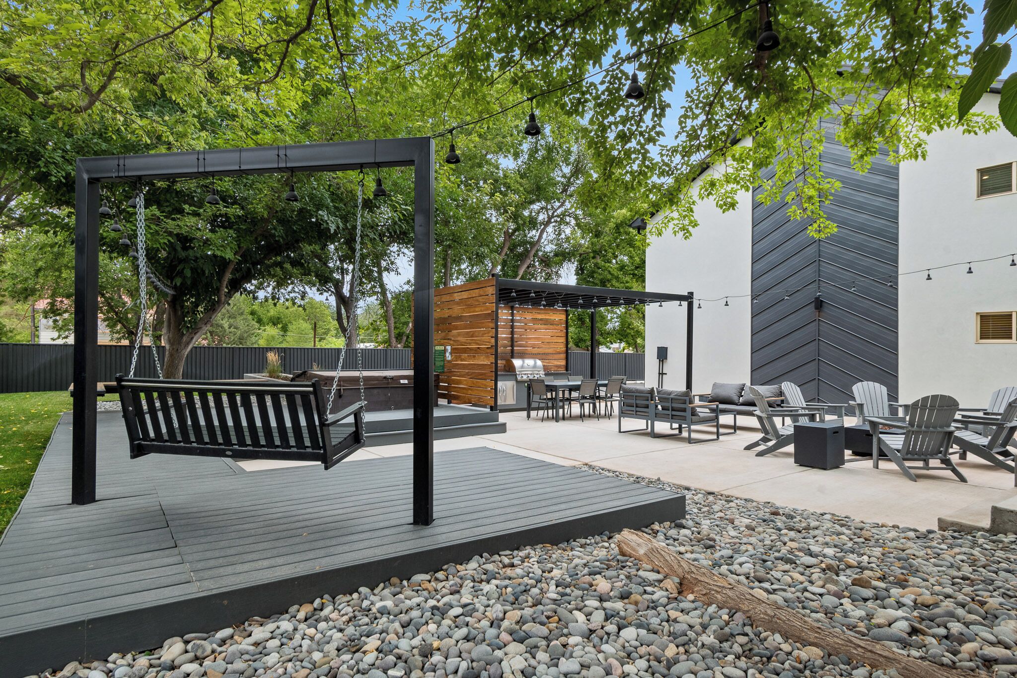Eine Terrasse im Freien mit einer Schaukel, Sitzgelegenheiten und einem Grill.