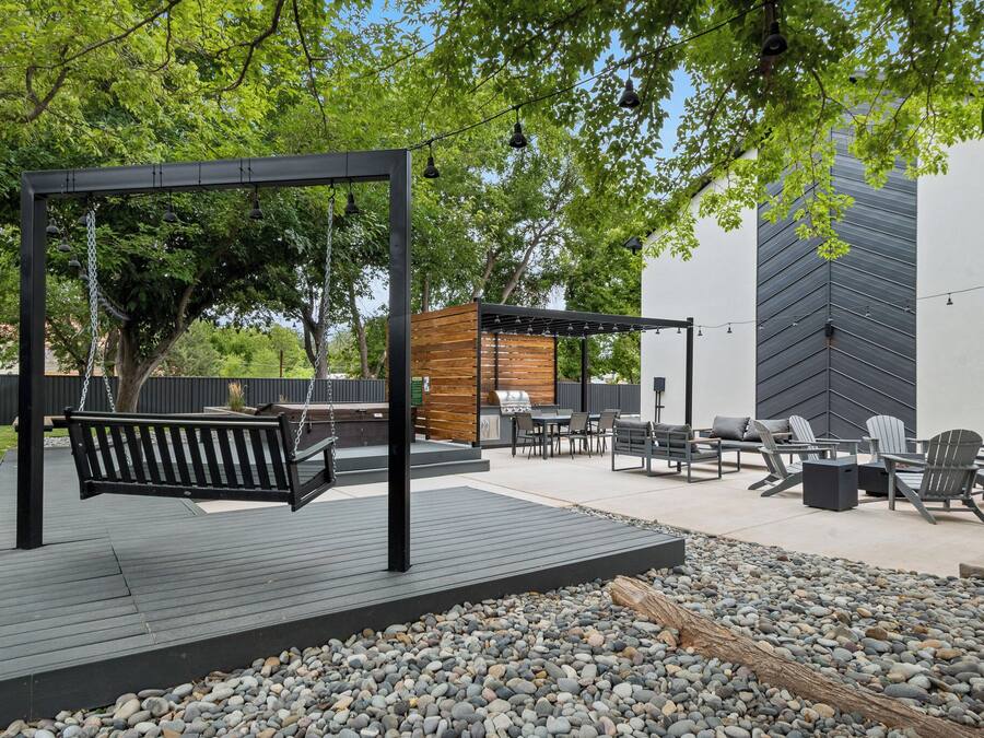 An outdoor patio with a swing, seating area, and barbecue grill.