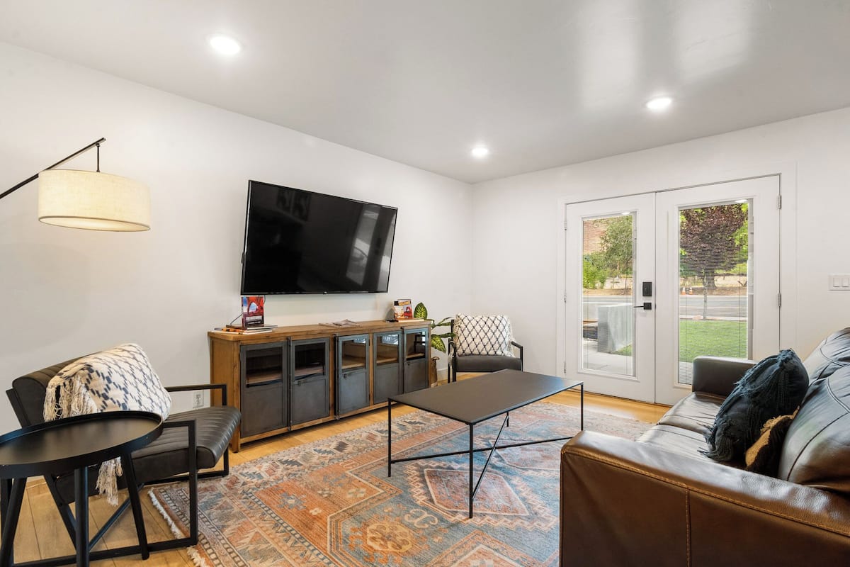 A modern living room with a flat-screen TV, a sofa, a coffee table, and a cabinet.