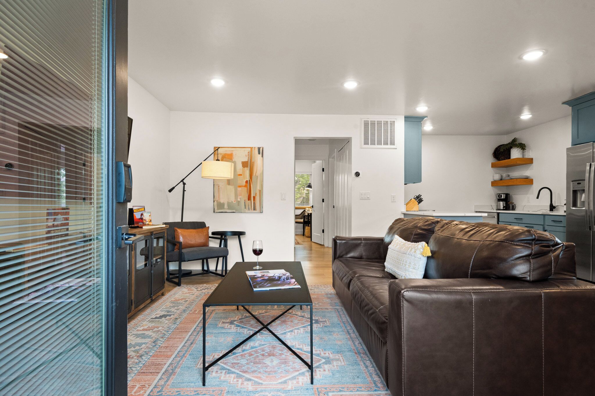 Uma sala de estar moderna com um sofá de couro marrom, uma mesa de centro e um espaço de jantar com mesa e cadeiras.
