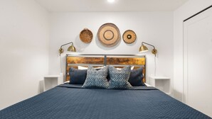 Ein ordentlich eingerichtetes Schlafzimmer mit einem großen Bett, einem Holz-Kopfteil und drei Wanddekorationen.