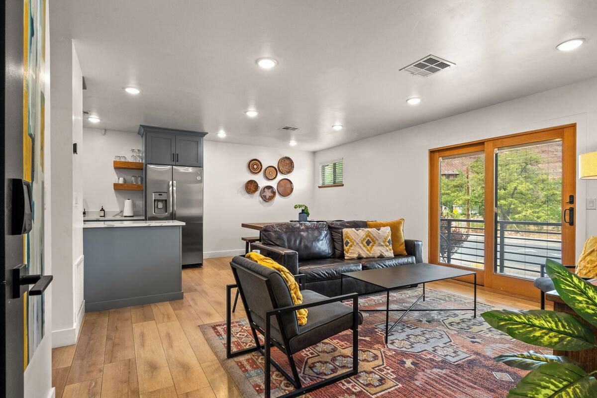 A modern kitchen with a refrigerator, cabinets, and a dining area with a sofa and coffee table.