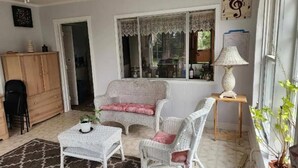 A cozy room with wicker furniture, a small table, and a window with lace curtains.