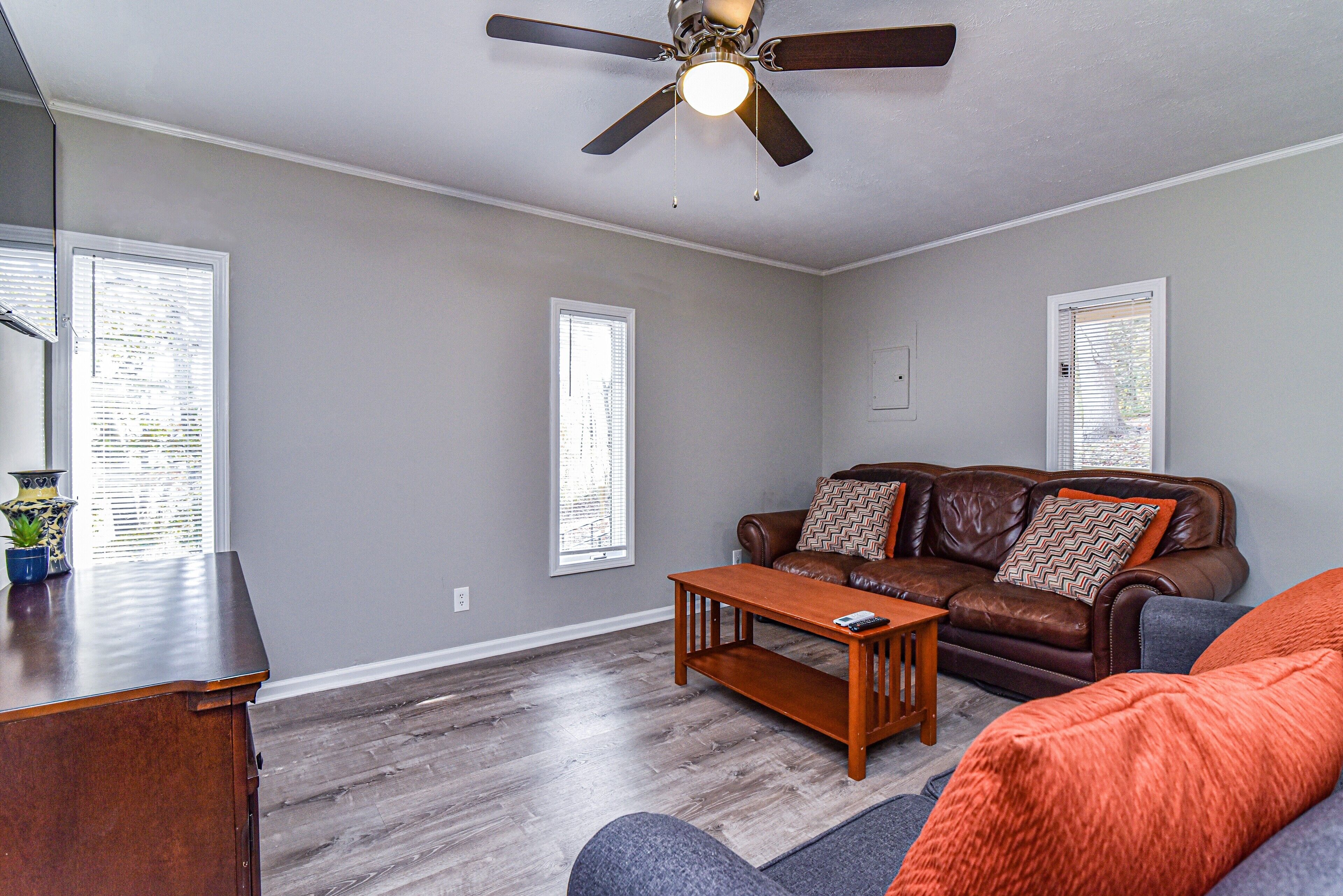 A living room with a brown leather sofa, a wooden coffee table, and a ceiling fan.