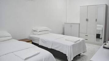 Habitación de hotel con dos camas individuales, un armario, una mesita y un espejo.