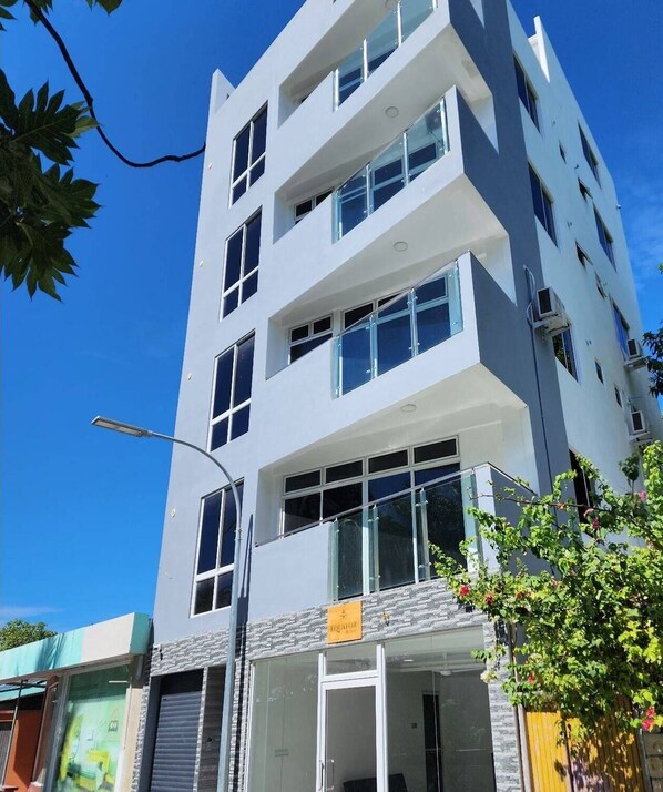 A multi-story building with a modern architectural design, featuring large windows and a flat facade.