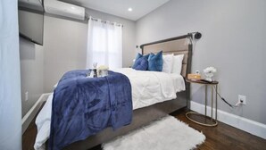 Una camera da letto con un letto, un comodino, una lampada e un condizionatore d'aria a parete.