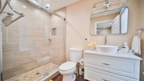 Un bagno moderno con doccia vetrata, un water bianco e un mobile lavabo con cassetti e specchio.
