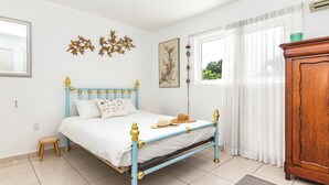 A bedroom with a bed, a wooden cabinet, and a window with curtains.