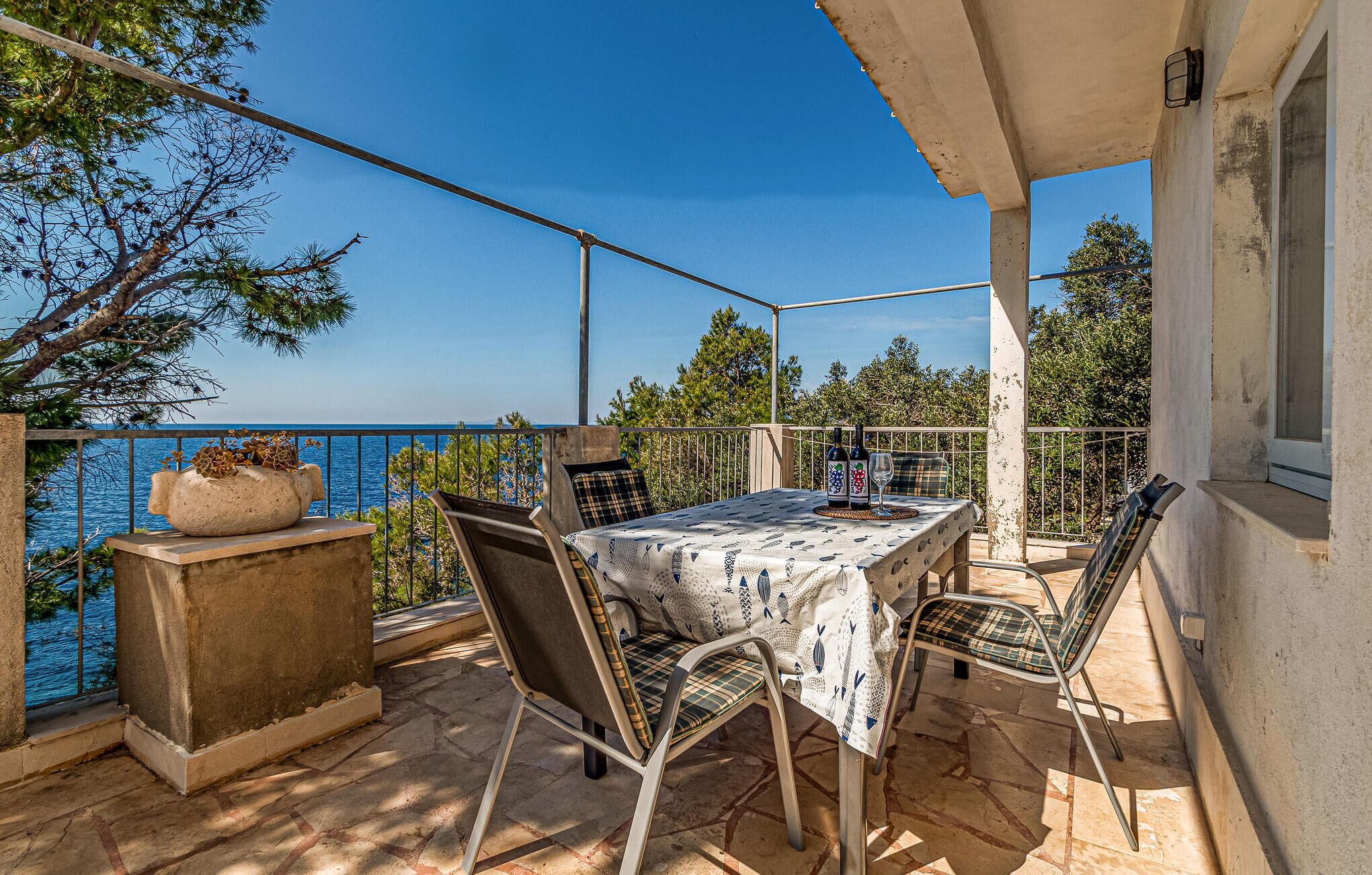 A balcony with a table and chairs, overlooking a body of water.