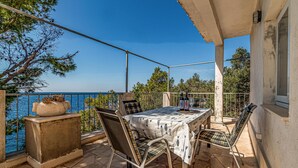A balcony with a table and chairs, overlooking a body of water. - Gorgeous apartment in Potomje with house sea view (Potomje)
