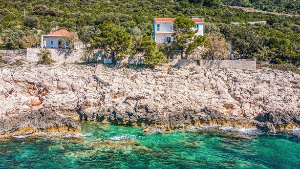 A coastal property with two buildings, a rocky shoreline, and clear turquoise waters. - Gorgeous apartment in Potomje with house sea view (Potomje)