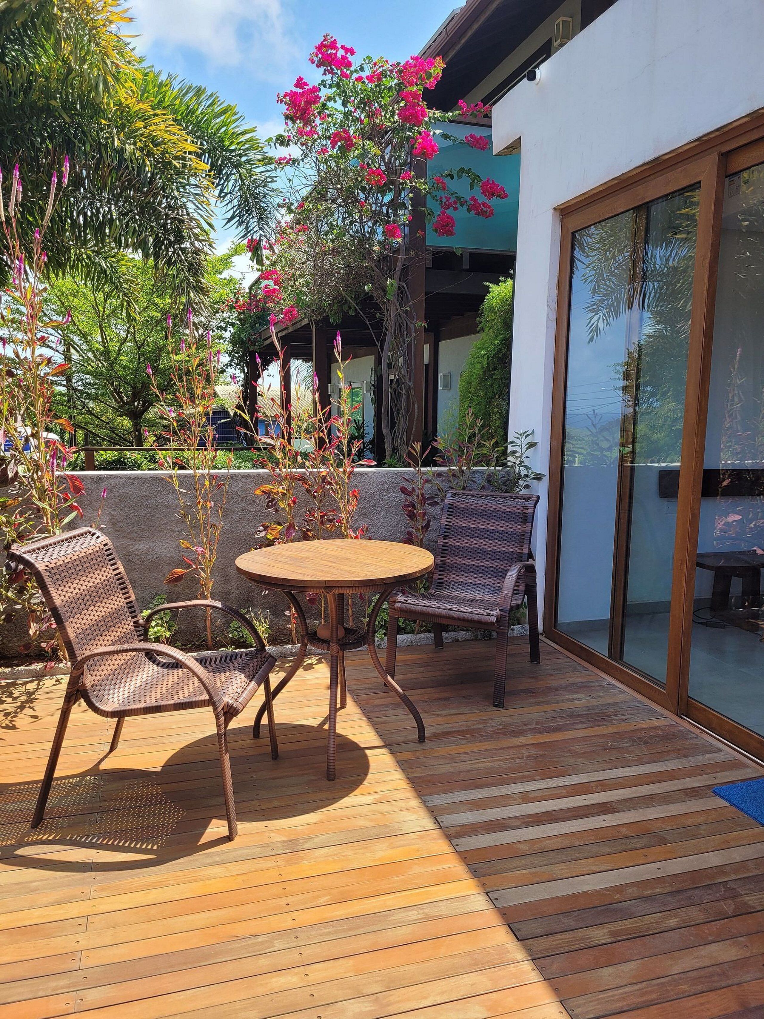 An outdoor patio with wicker furniture, a round table, and a glass door leading to an interior space.