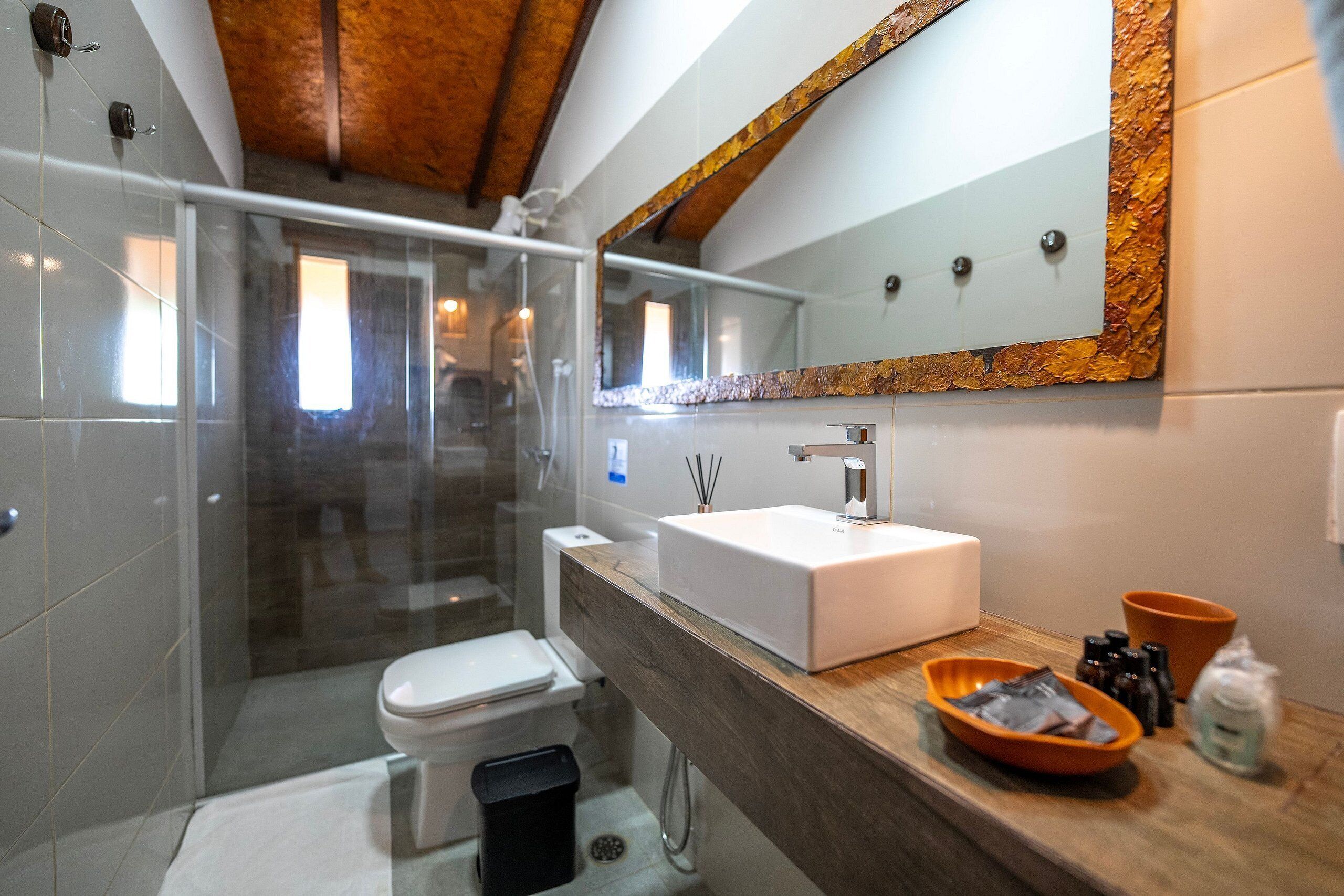 A modern bathroom with a glass shower enclosure, a white sink, and a wooden vanity.
