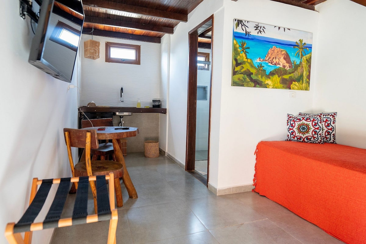 Une pièce comprenant un lit, un bureau, une chaise, un téléviseur et un tableau accroché au mur.