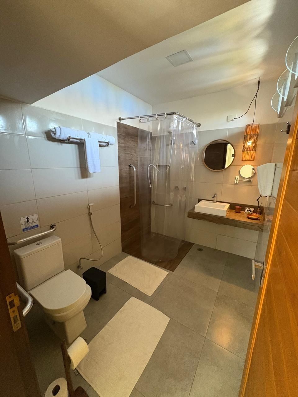 A modern bathroom with a toilet, shower, sink, and a mirror.