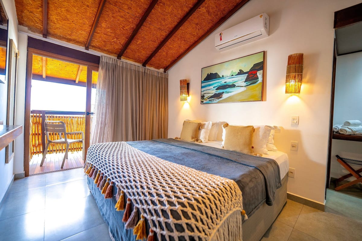 Une chambre à coucher avec un lit, un balcon, un tableau et une lampe fixée au mur.