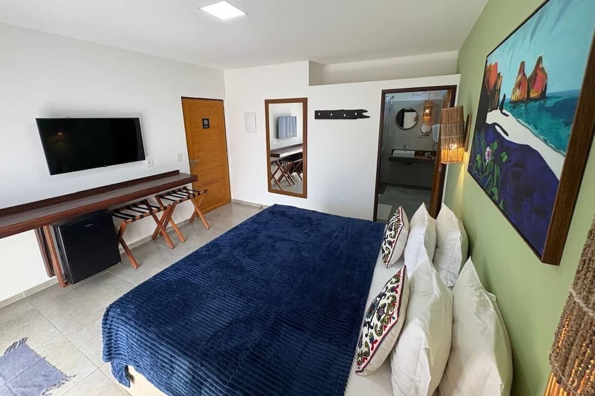 Une chambre à coucher avec un lit, une télévision, un bureau et un tableau.