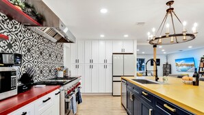 A modern kitchen with white cabinets, a red countertop, and a patterned backsplash. - Luxury 20-Acre Estate Pool, Spa, Game Room Sleeps 14 Near Joshua Tree NP (Joshua Tree)