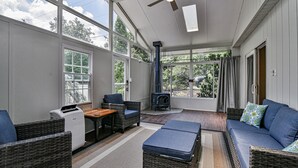 A sunroom with wicker furniture, a fireplace, and large windows. - 2 BR apt near Mtn to Sea Hiking Trail (Asheville)