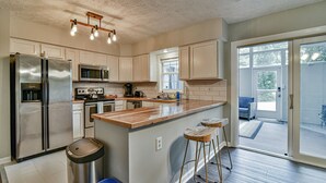 A modern kitchen with stainless steel appliances, wooden bar stools, and a large island. - 2 BR apt near Mtn to Sea Hiking Trail (Asheville)