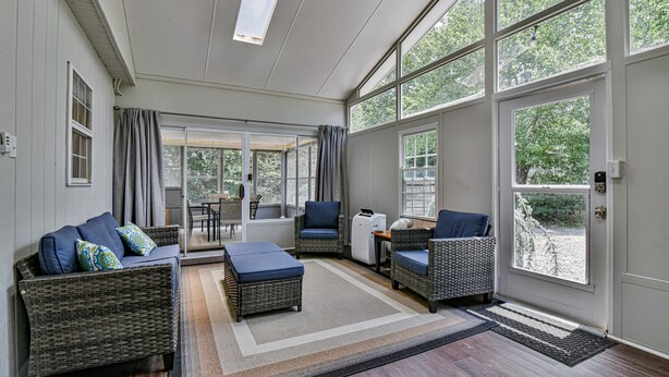 A spacious living area with wicker furniture, large windows, and a view of the outdoors. - 2 BR apt near Mtn to Sea Hiking Trail (Asheville)