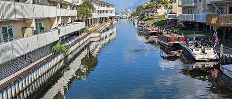Un canal bordé de bâtiments des deux côtés, des bateaux amarrés le long de l’eau et un ciel dégagé.