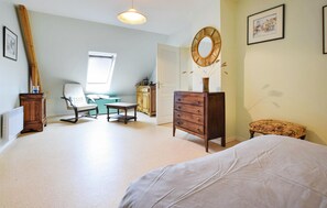 Cozy retreat with a large bed, dresser, and comfortable chair.