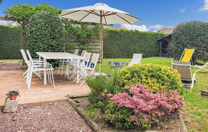 Enjoy dining or socializing in this serene garden setting, surrounded by lush greenery and a shaded patio area.