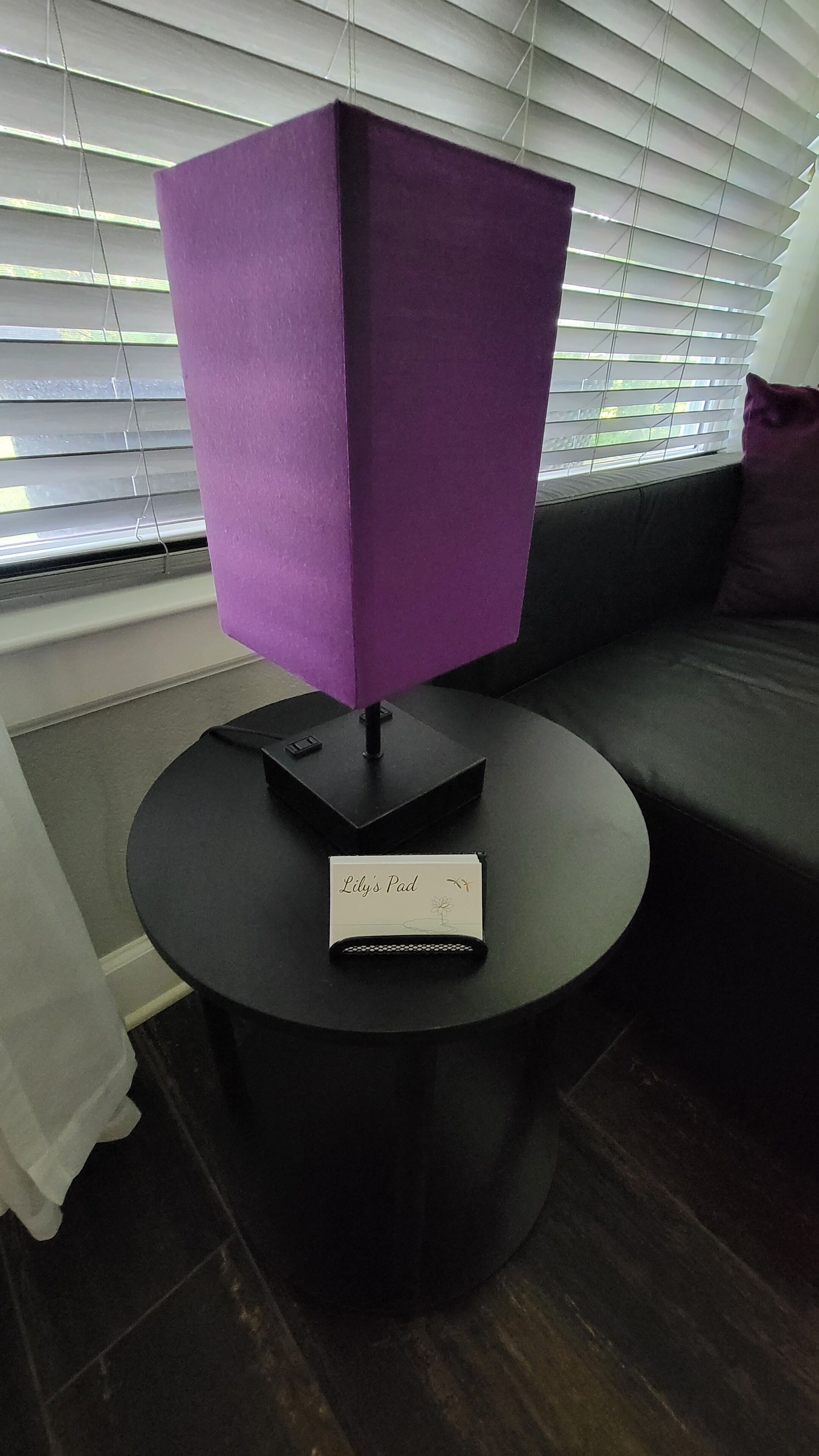 Una lámpara morada sobre una mesa negra con un letrero que dice 'Lily's Pad'.