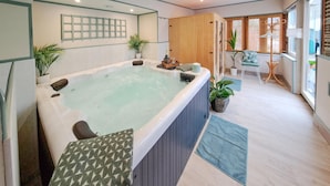 A modern bathroom with a freestanding bathtub, wooden paneling, and potted plants. - Gorgeous home in Thierville (Thierville)