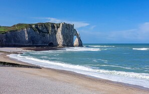 Un paisaje costero con una imponente formación rocosa y una playa.