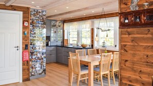 A cozy kitchen with wooden cabinets, a dining table with chairs, and a wall decorated with photos. - 5 bedroom stunning home in Passebekk (Passebekk)