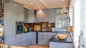 A modern kitchen with grey cabinets, stainless steel appliances, and a wooden island. - 5 bedroom stunning home in Passebekk (Passebekk)