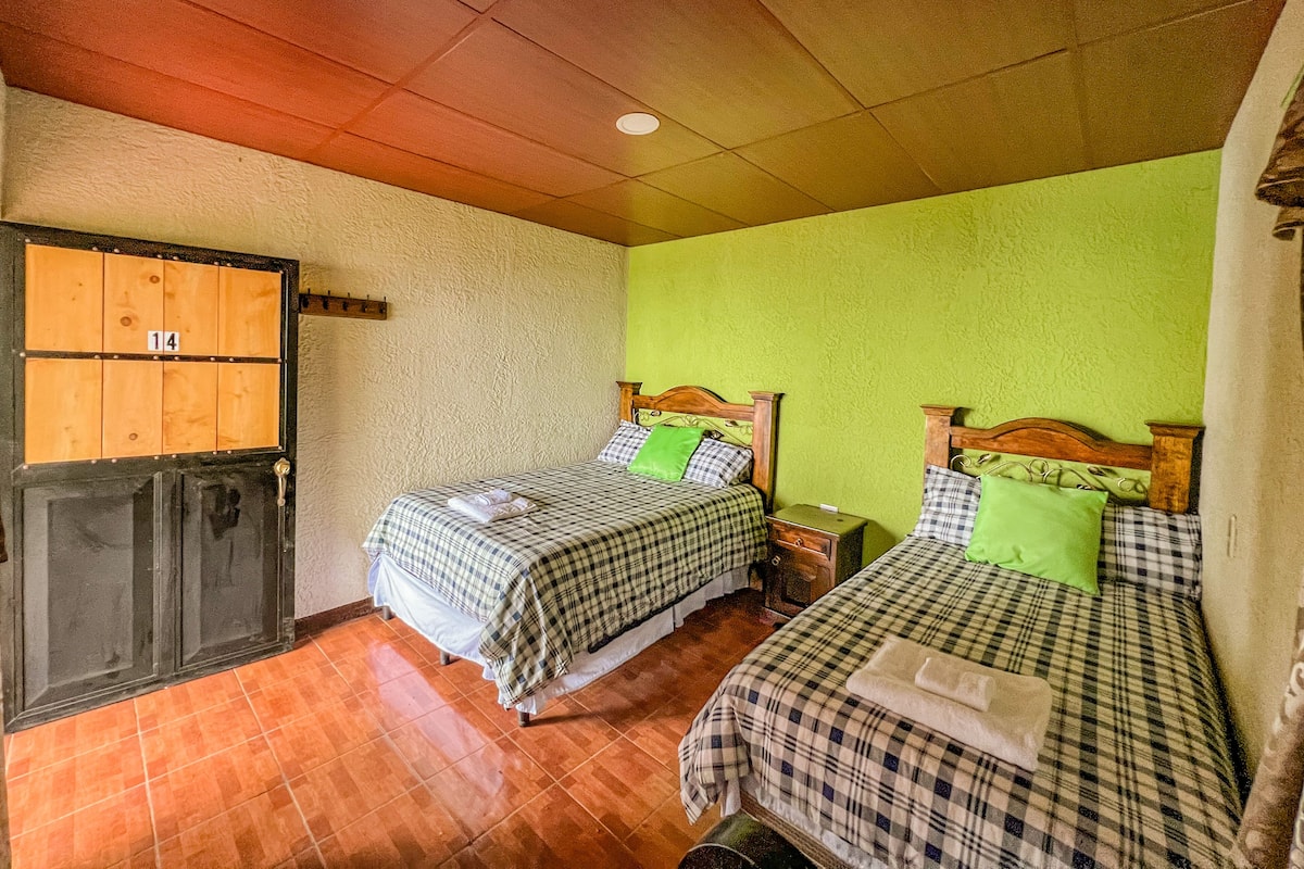 A room with two beds, a wooden door with a number, and a green wall.