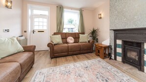 A living room with a brown leather sofa, a patterned rug, a fireplace, and a door with curtains.