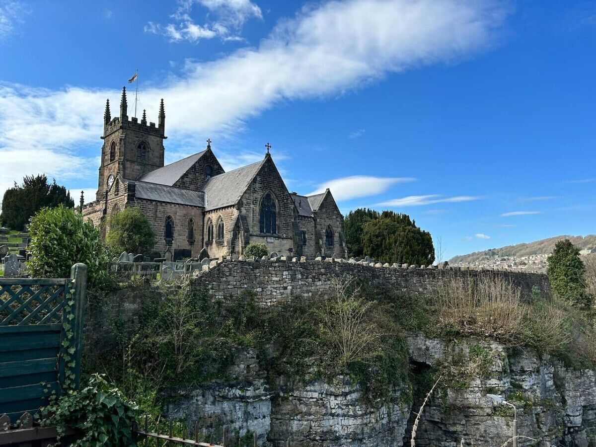 A historic stone church with a prominent tower and a stone wall in the foreground.