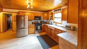 A modern kitchen with wooden cabinets, stainless steel appliances, and a granite countertop. - Secluded 3BR Cabin • Fire Pit • RV Parking • Near Tippy Dam & Big-M Trails (Wellston)