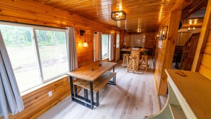 A wooden cabin interior with a dining table, benches, and a kitchen area. - Secluded 3BR Cabin • Fire Pit • RV Parking • Near Tippy Dam & Big-M Trails (Wellston)