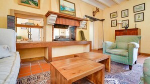 Een gezellige woonkamer met een houten salontafel, een groene fauteuil en een open haard.