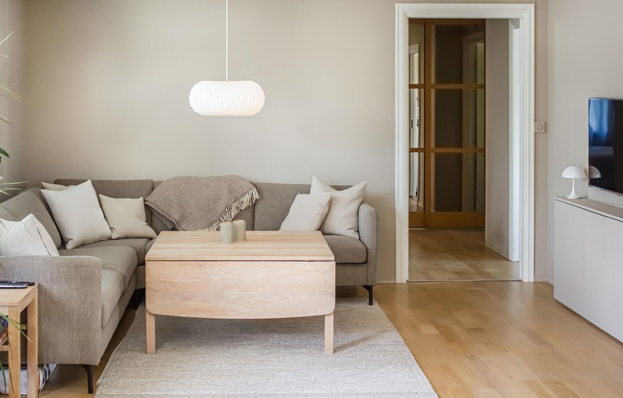 A modern living room with a sofa, a coffee table, and a hanging light fixture.