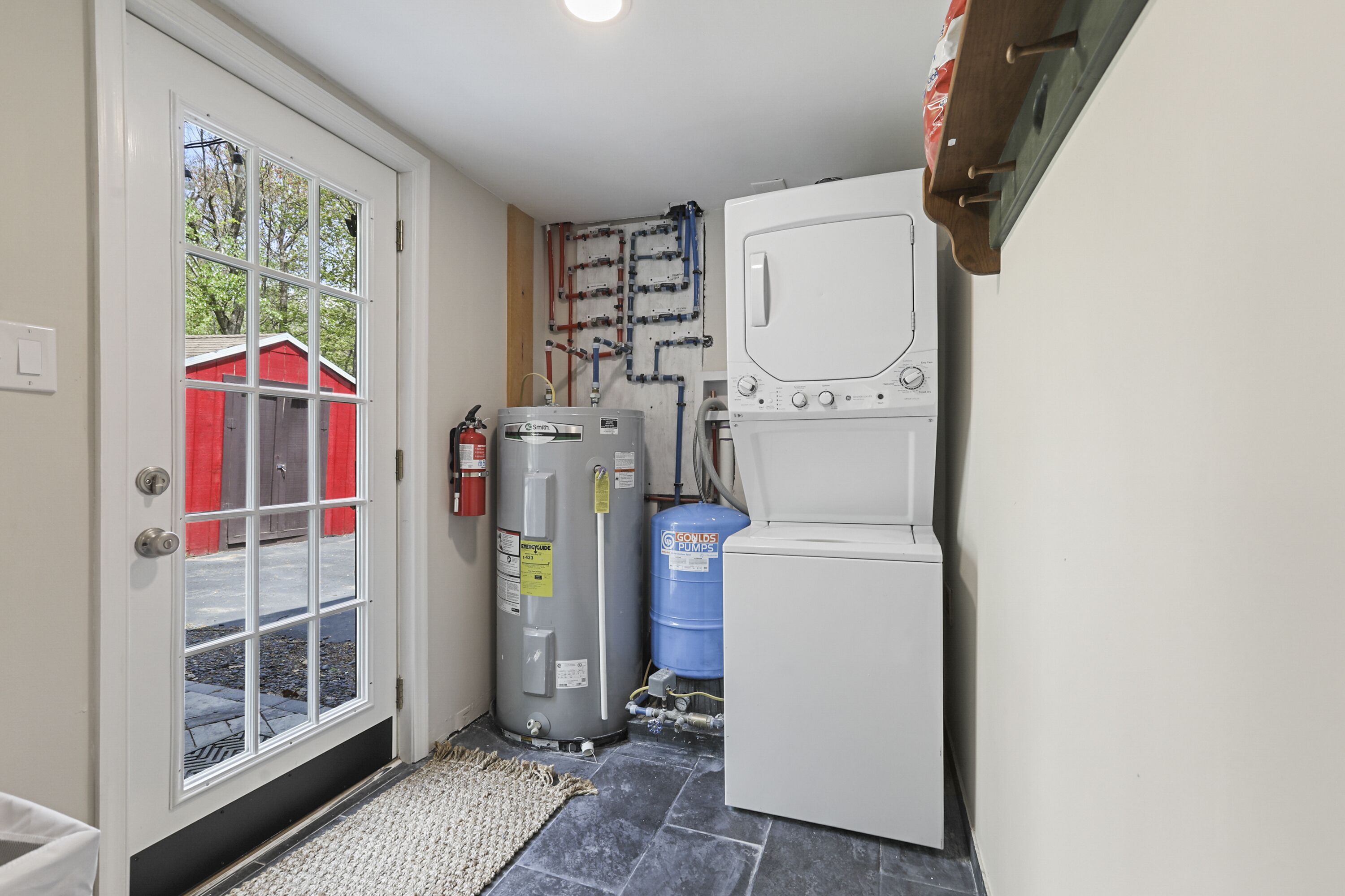 A compact utility room with a water heater, a large water tank, and a washing machine.